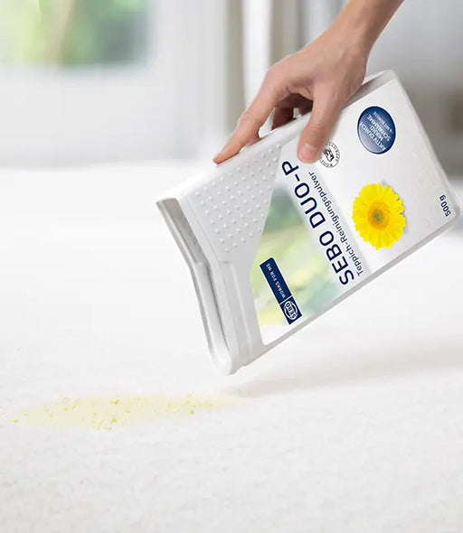 Person using a Sebo Duo-P cleaning tool on a surface with a visible stain.
